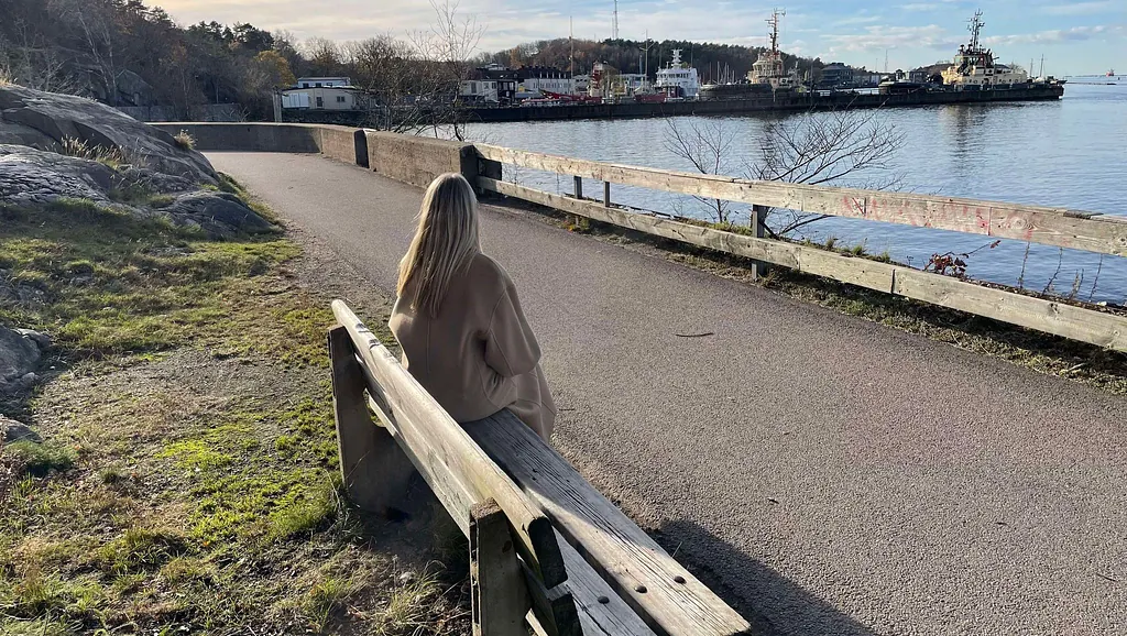 Kvinna sitter ensam och tittar ut över havet
